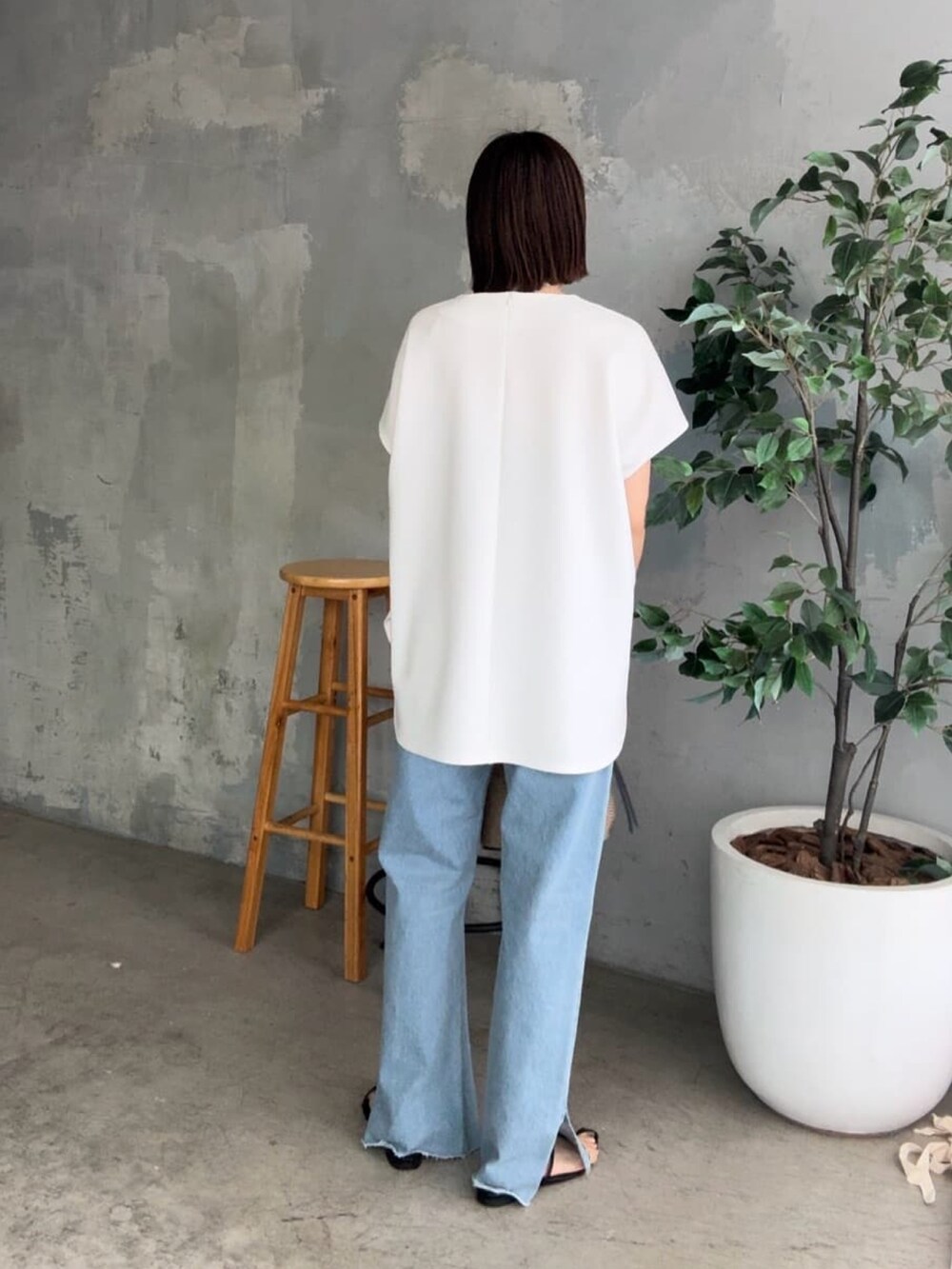 ブルー系のデニムパンツ、ブラック系のサンダル、ブラック系のハンドバッグを着用したレディースの春コーディネートの3枚目の写真