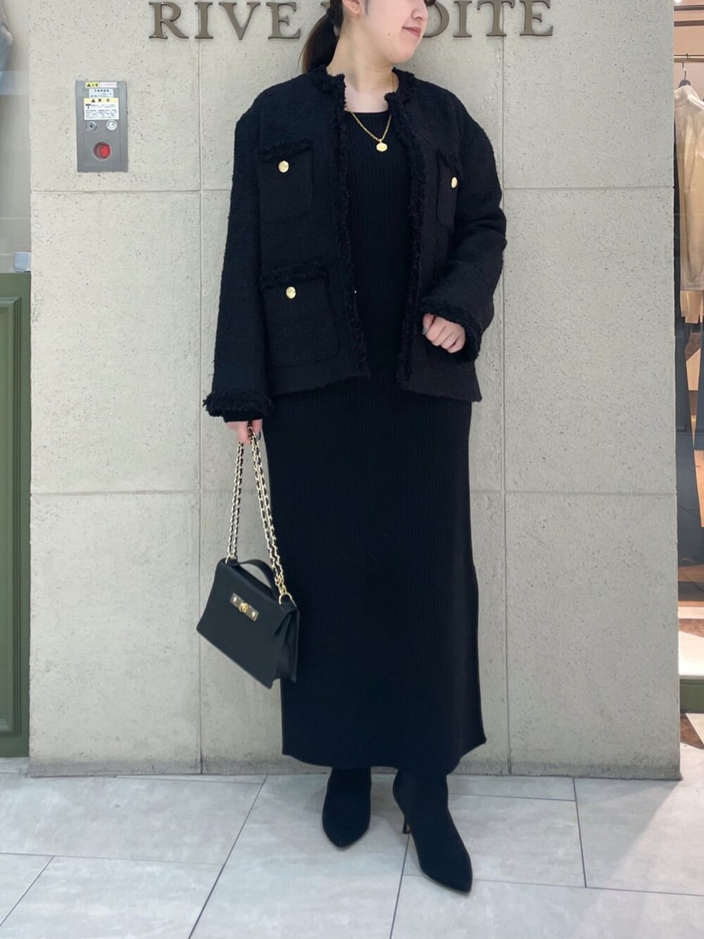 ブラック系のその他アウター、ブラック系のワンピース、ブラック系のハンドバッグを着用したレディースの冬コーディネートの2枚目の写真