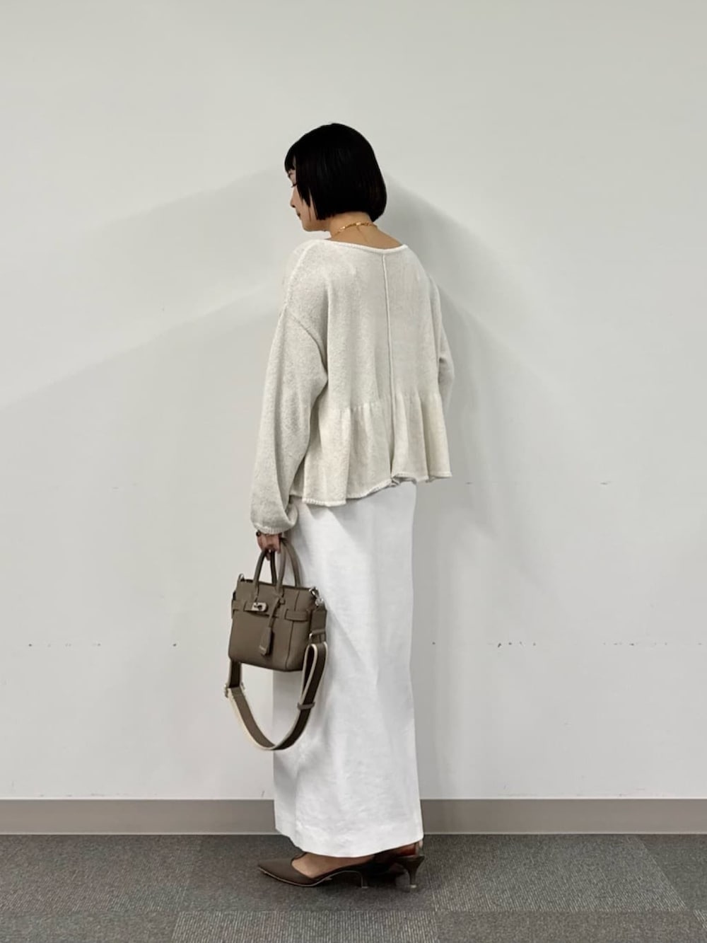 ホワイト系のニット/セーター、グレー系のトートバッグ、ホワイト系のスカートを着用したレディースの冬コーディネートの3枚目の写真