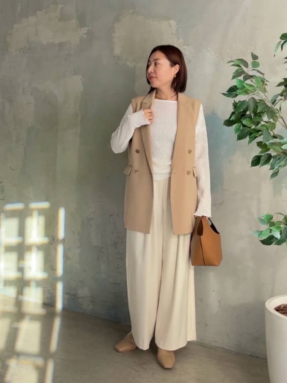 ホワイト系のTシャツ/カットソー、ベージュ系のベスト、イエロー系のハンドバッグを着用したレディースの冬コーディネートの4枚目の写真