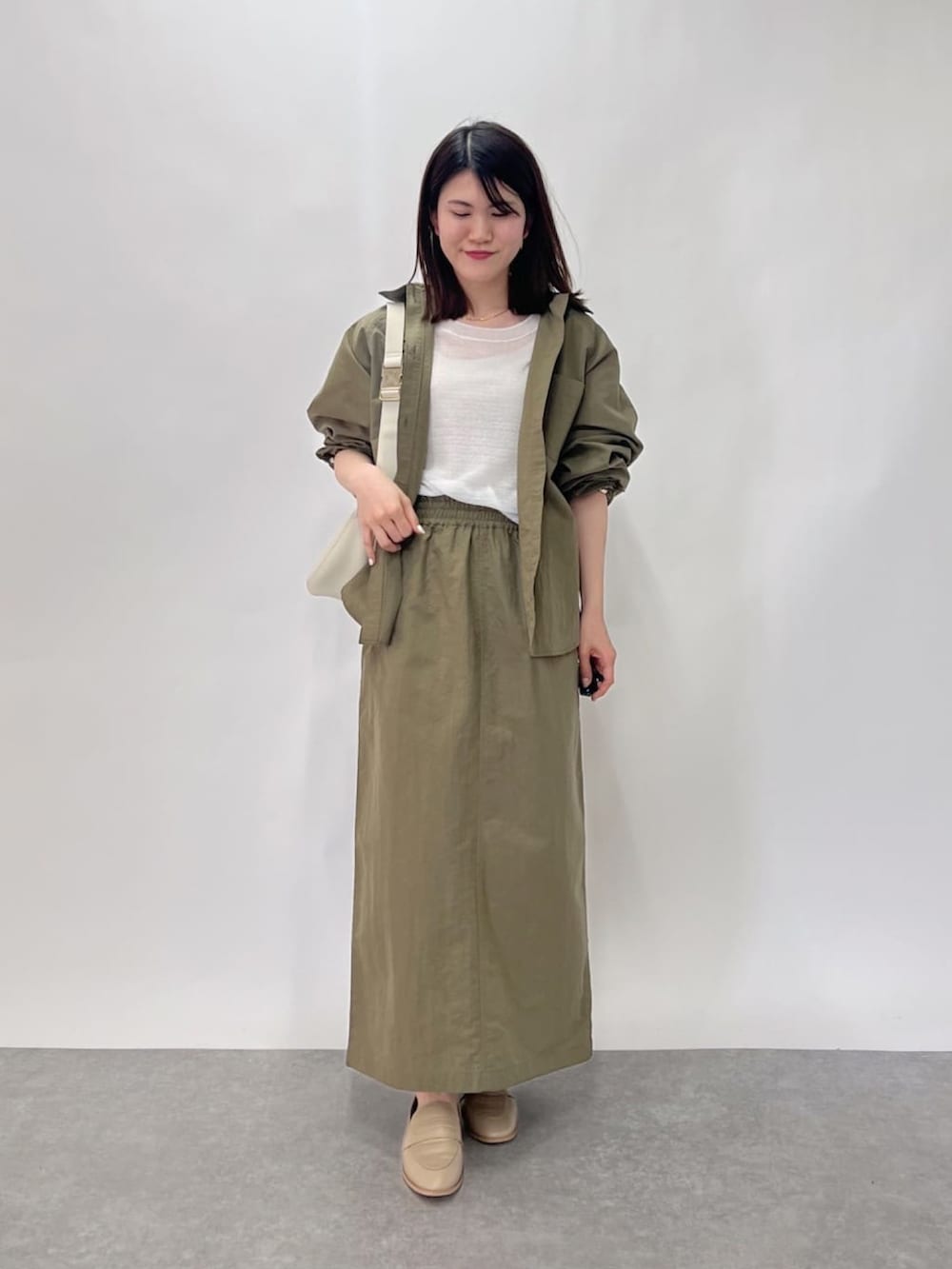 ホワイト系のニット/セーター、グリーン系のシャツ/ブラウス、グリーン系のスカートを着用したレディースの春コーディネートの2枚目の写真