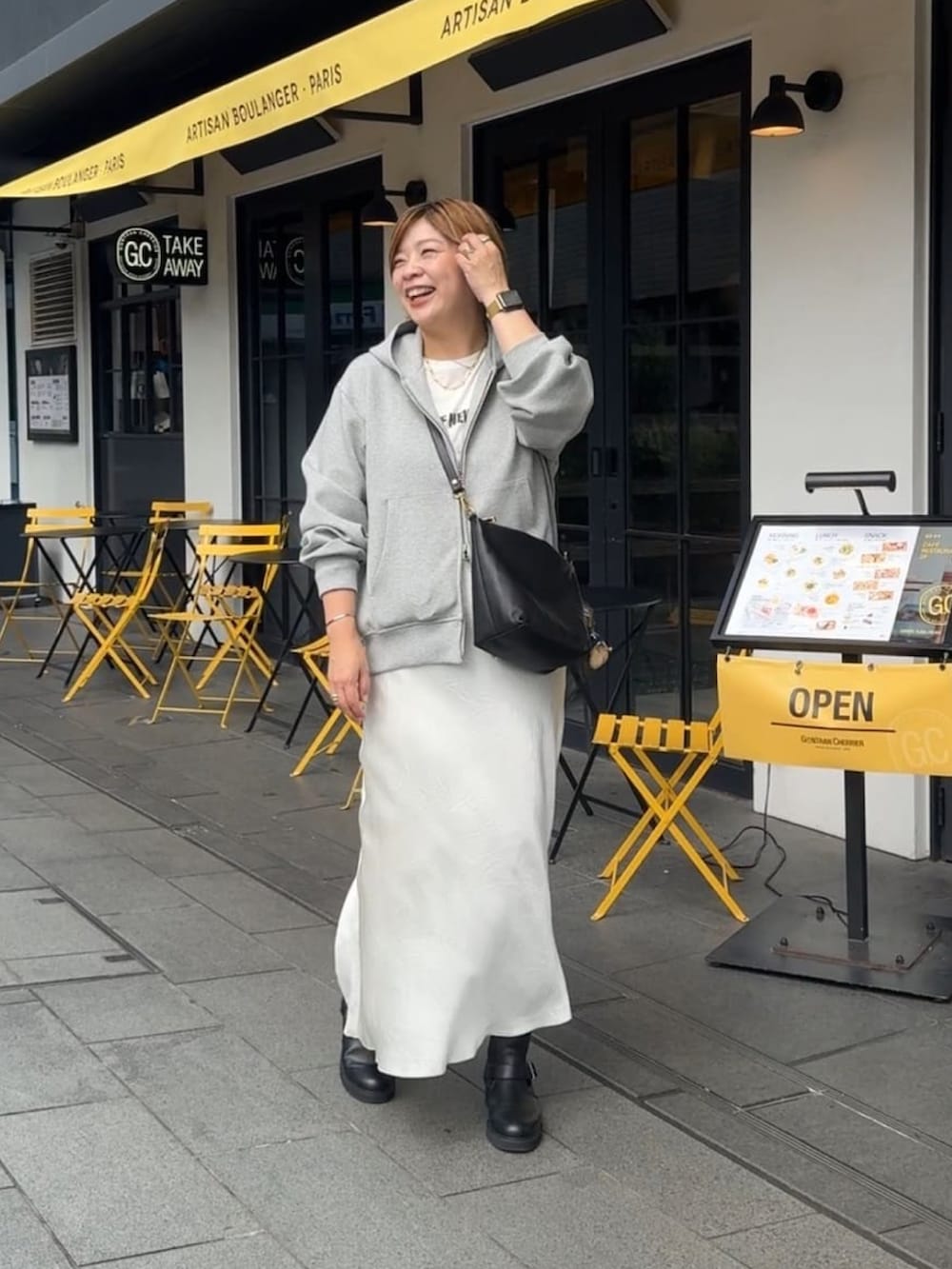 グレー系のパーカー、ホワイト系のスカートを着用したレディースの秋コーディネートの2枚目の写真