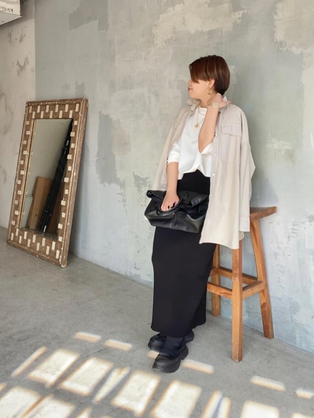 ブラック系のスカート、ホワイト系のTシャツ/カットソー、ブラック系のブーツを着用したレディースの冬コーディネートの2枚目の写真