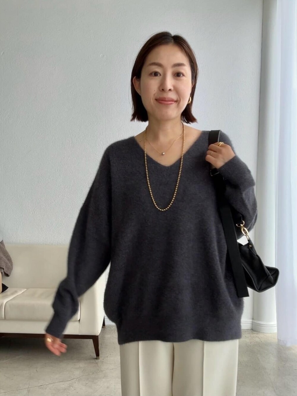 グレー系のニット/セーター、ブラック系のショルダーバッグ、ホワイト系のその他パンツを着用したレディースの秋コーディネートの4枚目の写真