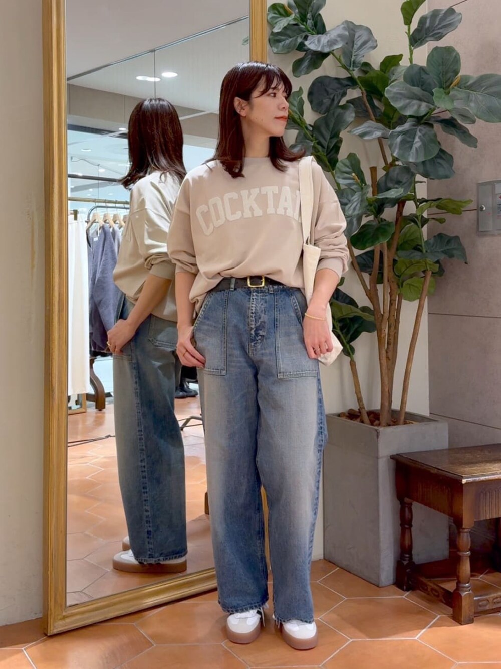 ベージュ系のスウェット、ホワイト系のトートバッグ、ブルー系のデニムパンツを着用したレディースの冬コーディネートの2枚目の写真