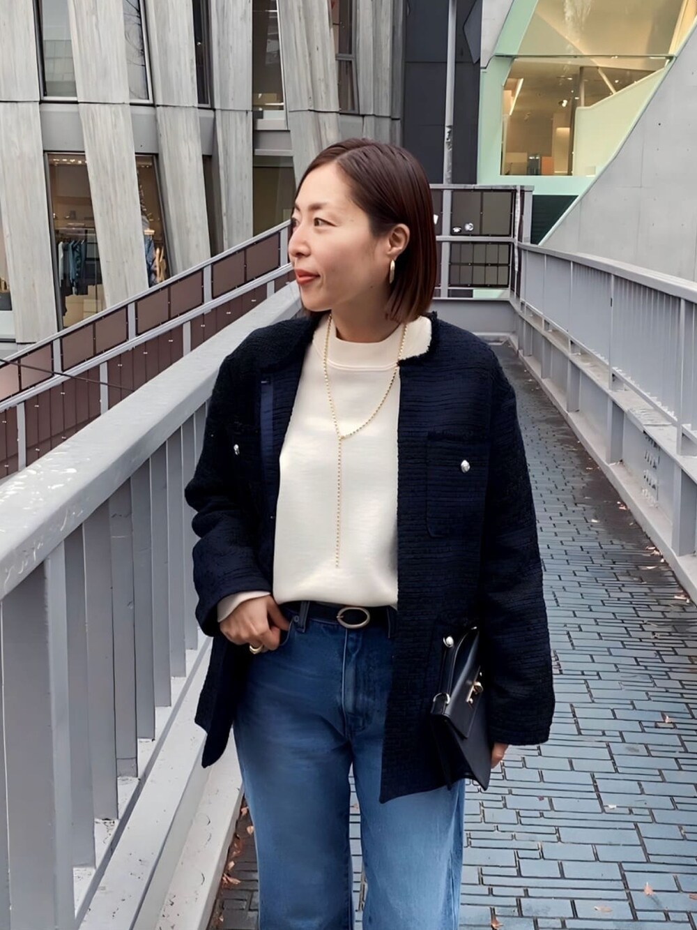 ホワイト系のニット/セーター、ブルー系のノーカラージャケット、ブラック系のハンドバッグを着用したレディースの冬コーディネートの4枚目の写真