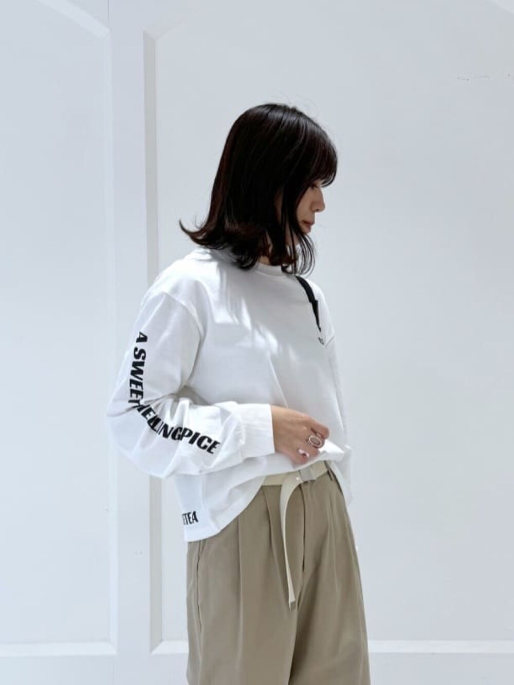 ベージュ系のチノパンツ、ホワイト系のTシャツ/カットソー、ブラック系のボディバッグ/ウエストポーチを着用したレディースの冬コーディネートの3枚目の写真