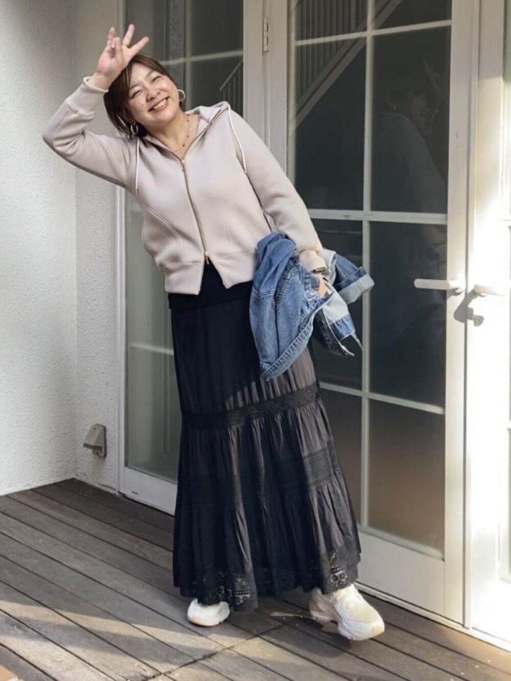 ベージュ系のパーカー、ブラック系のスカートを着用したレディースの秋コーディネートの2枚目の写真