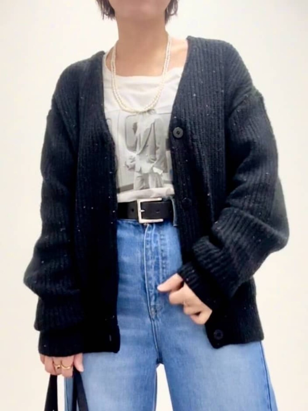 ブラック系のショルダーバッグ、グレー系のパンプス、ブルー系のデニムパンツを着用したレディースの秋コーディネートの6枚目の写真