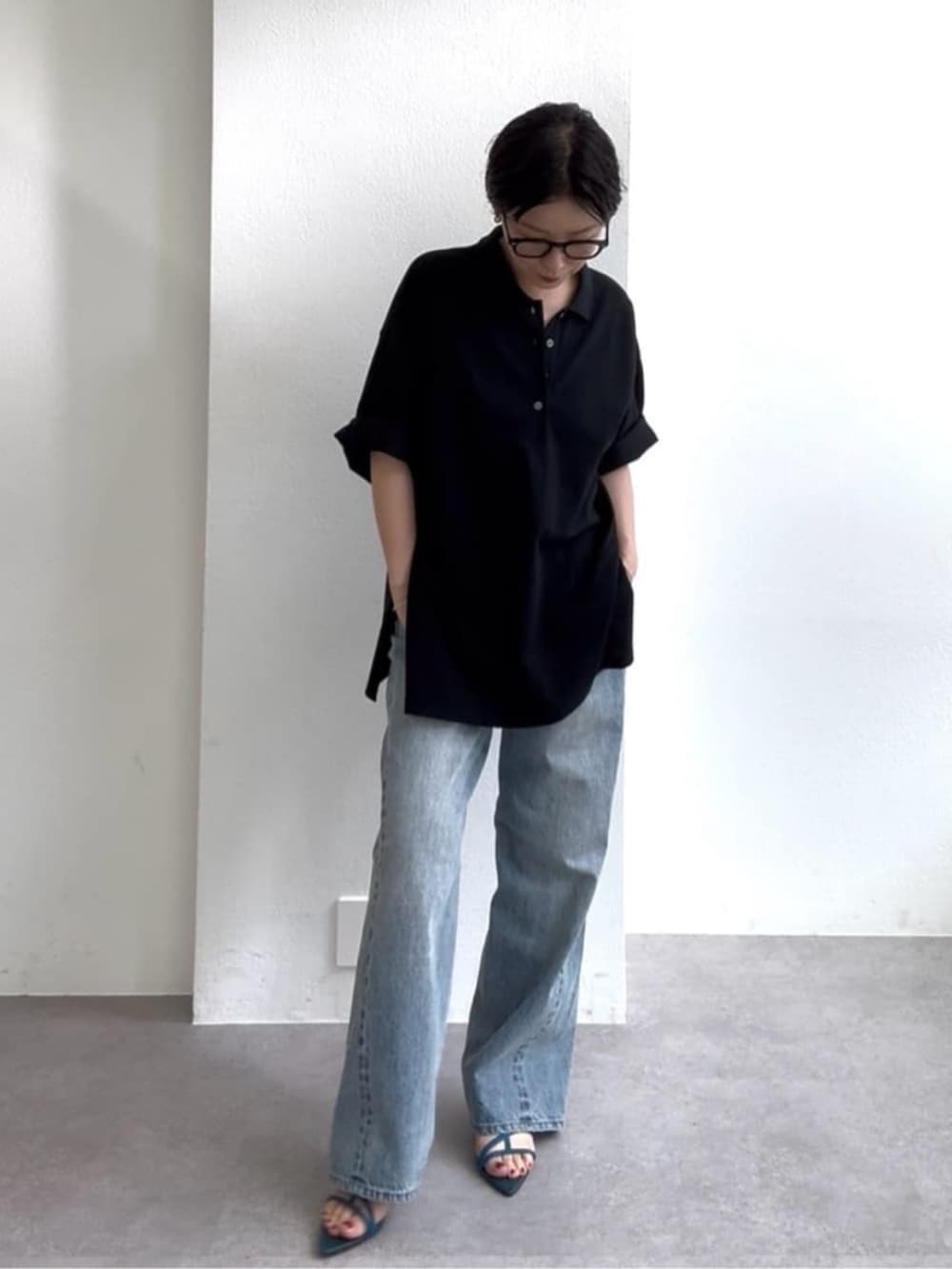 ブルー系のデニムパンツ、ブルー系のサンダル、ブラック系のポロシャツを着用したレディースの春コーディネートの6枚目の写真