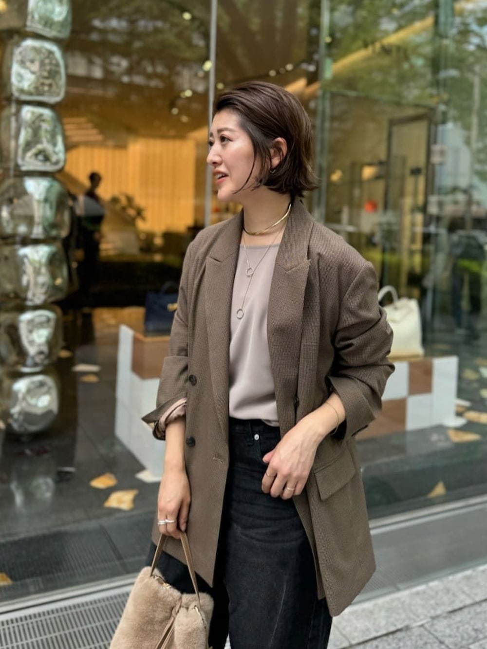 ブラック系のデニムパンツ、ベージュ系のハンドバッグ、ブラック系のサンダルを着用したレディースの夏コーディネートの3枚目の写真