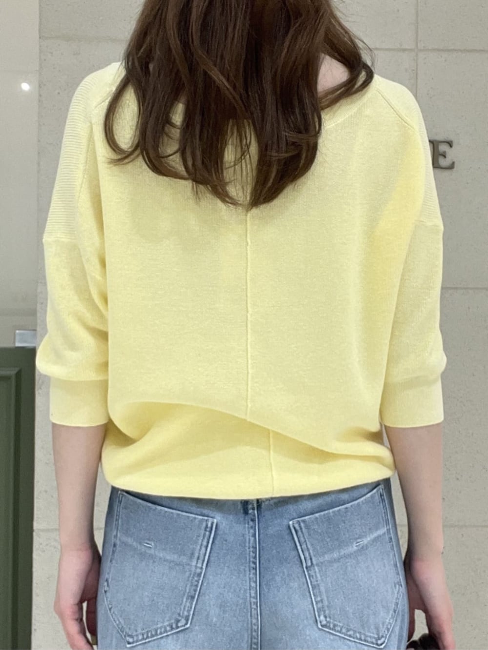 ブラウン系のボストンバッグ、イエロー系のニット/セーター、ブルー系のデニムパンツを着用したレディースの春コーディネートの6枚目の写真