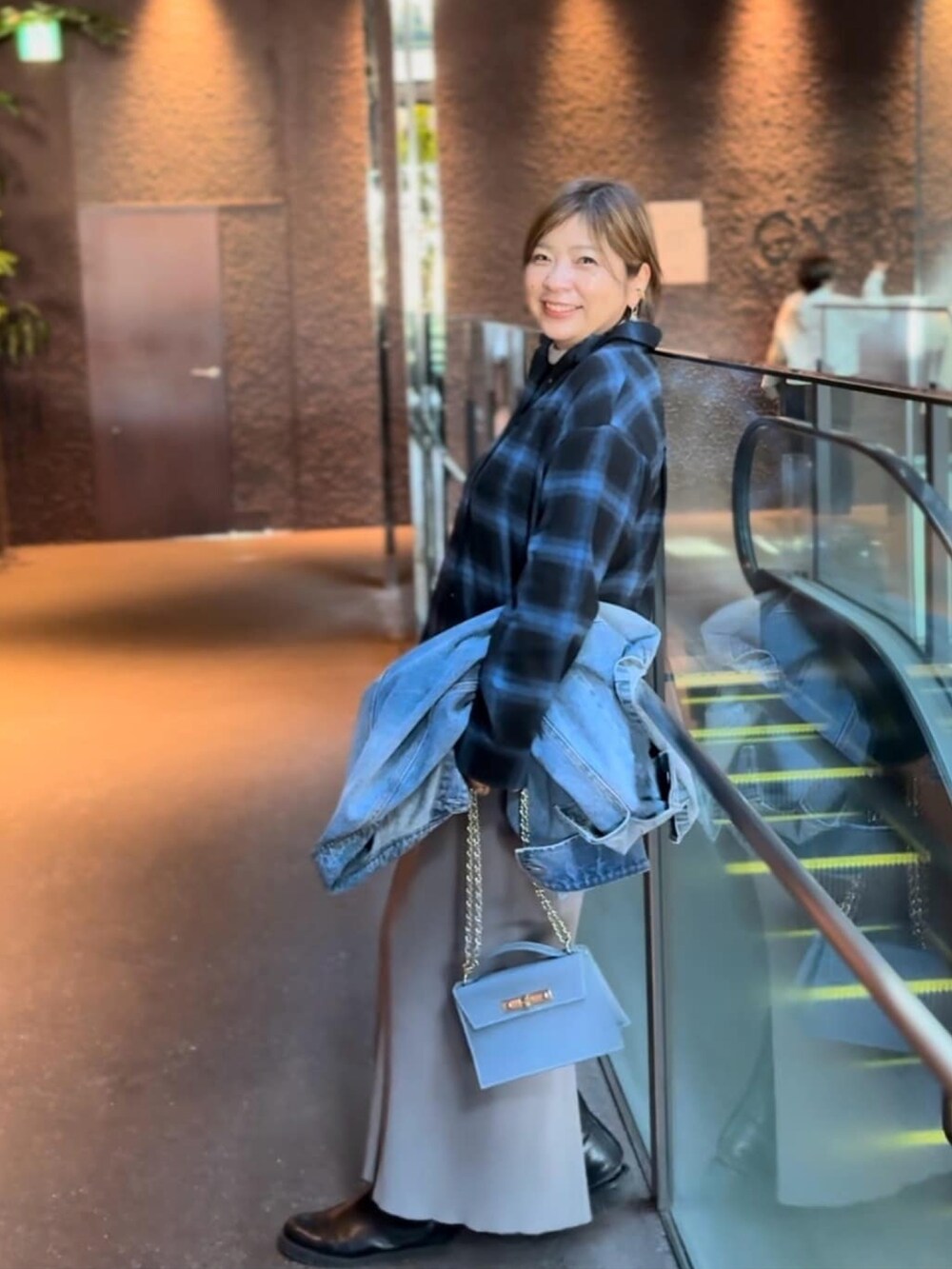 ブルー系のシャツ/ブラウス、グレー系のスカート、ブラック系のブーツを着用したレディースの冬コーディネートの2枚目の写真