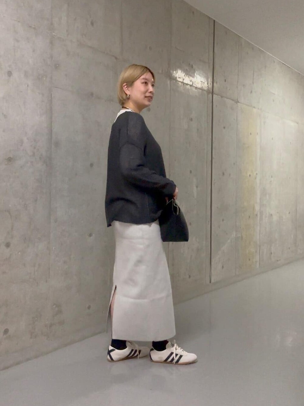 グレー系のニット/セーター、グレー系のスカート、ブラック系のハンドバッグを着用したレディースの冬コーディネートの2枚目の写真