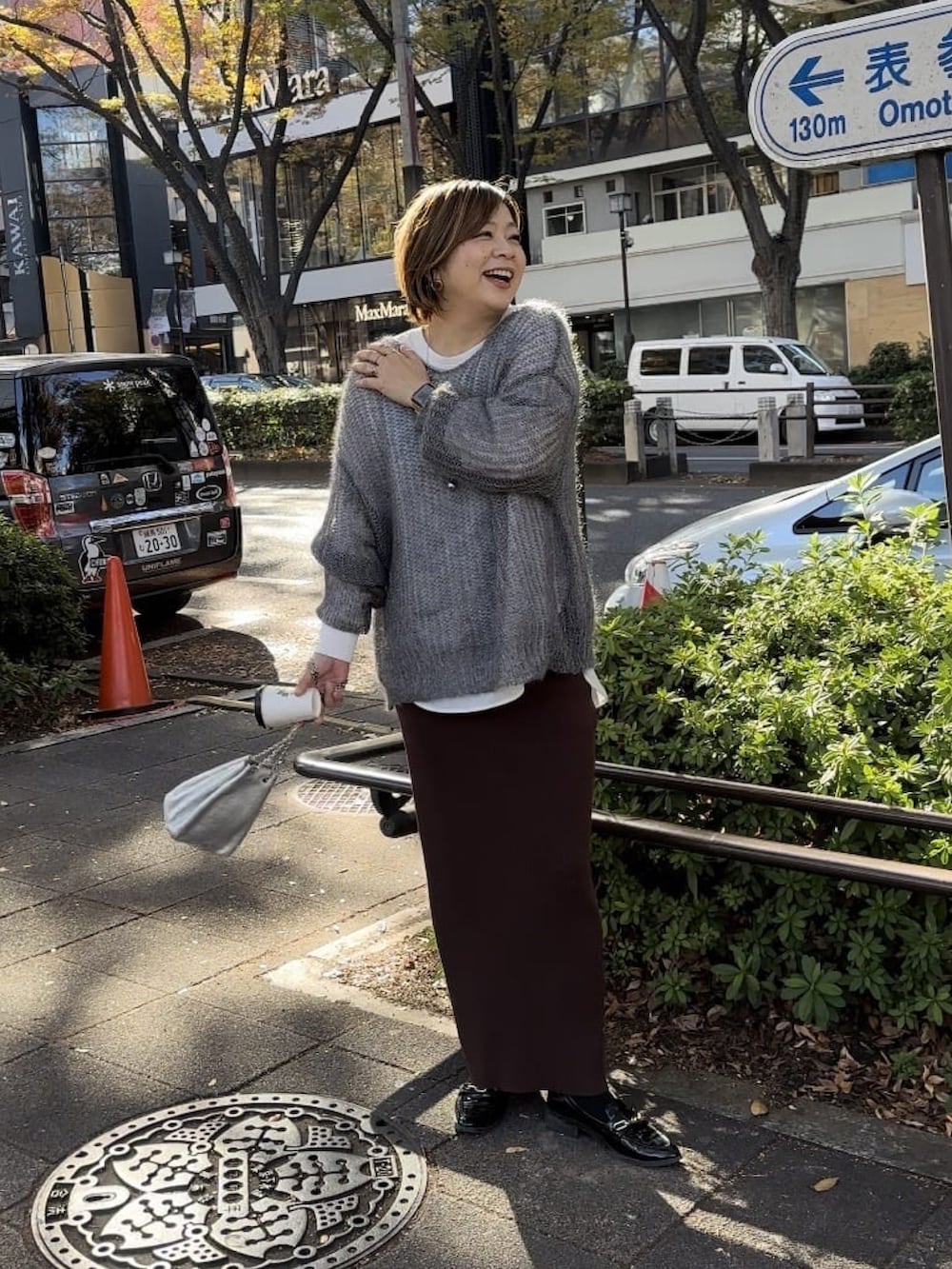 グレー系のニット/セーター、ホワイト系のシャツ/ブラウス、シルバー系のショルダーバッグを着用したレディースの冬コーディネートの3枚目の写真