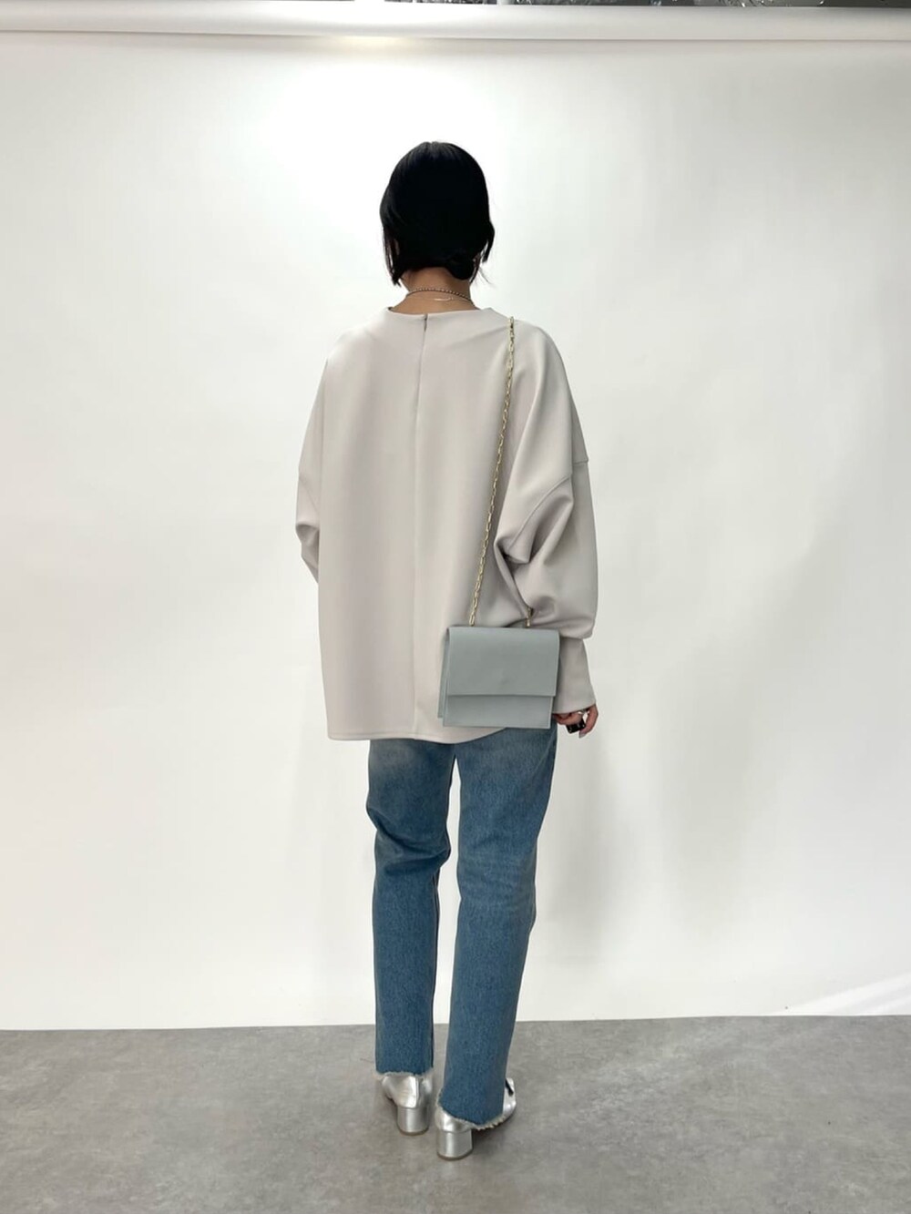 グレー系のTシャツ/カットソー、ブルー系のショルダーバッグ、ブルー系のデニムパンツを着用したレディースの冬コーディネートの3枚目の写真