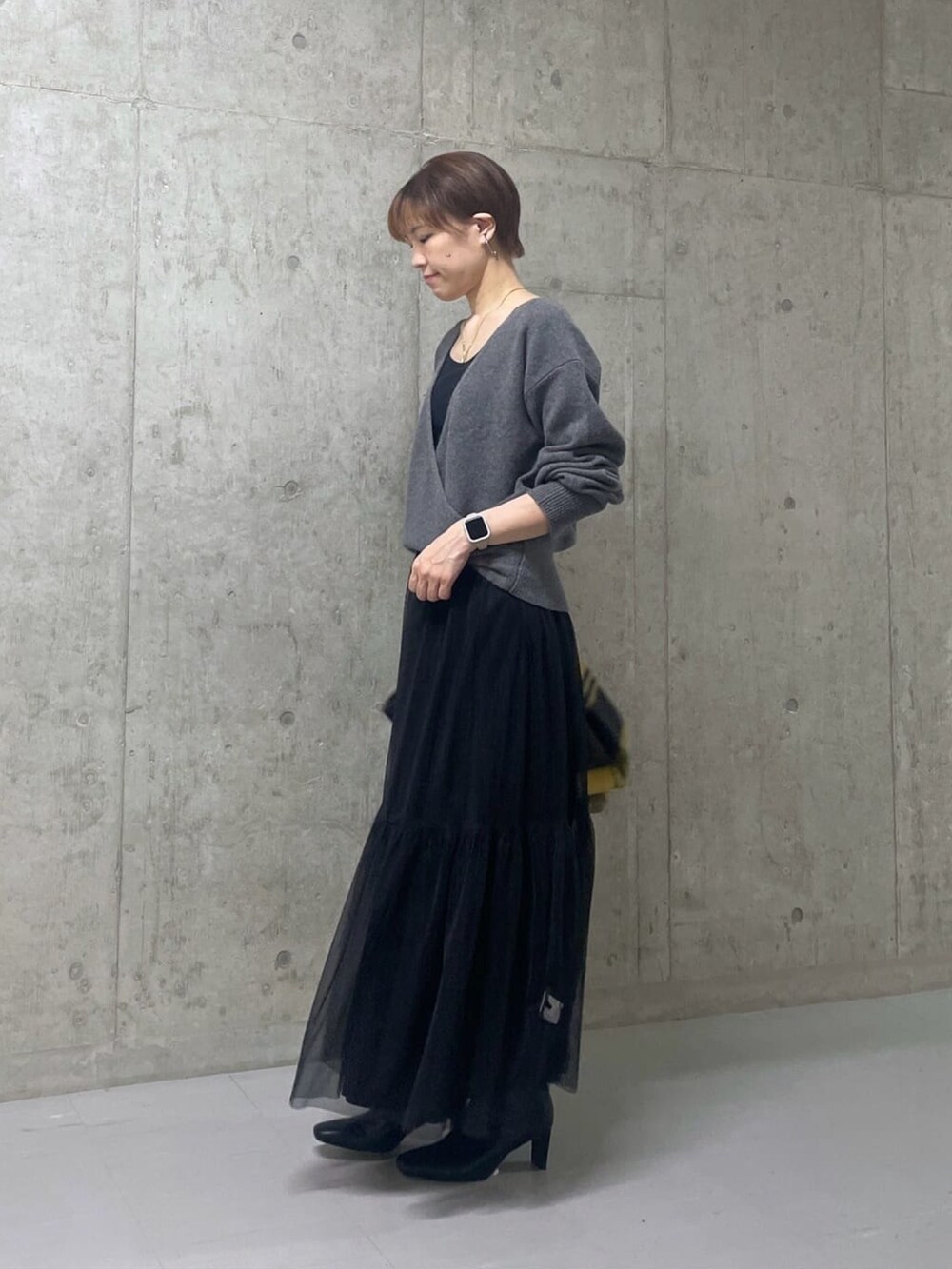グレー系のニット/セーター、ブラック系のスカート、ブラック系のブーツを着用したレディースの秋コーディネートの2枚目の写真