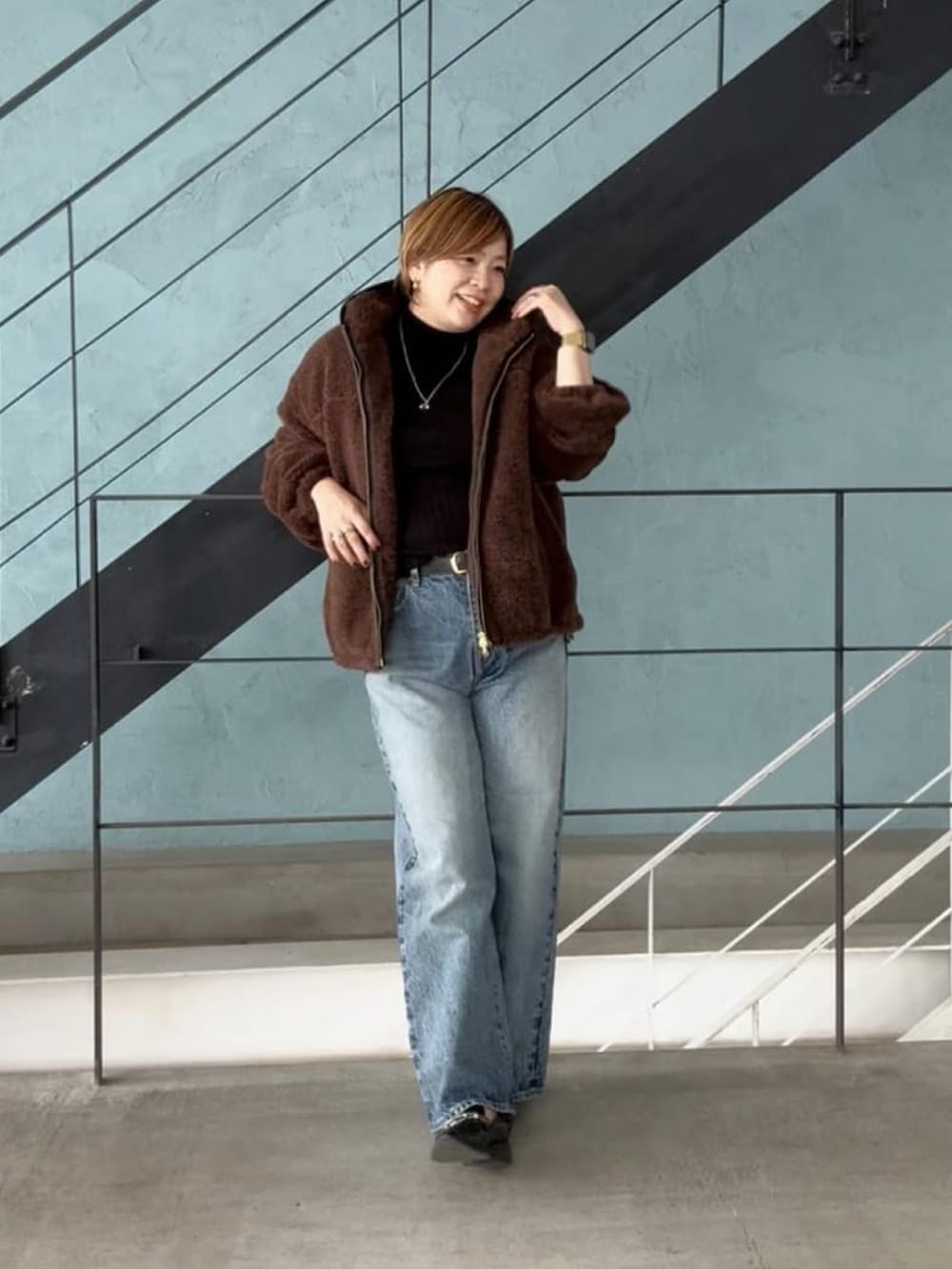 ブラック系のニット/セーター、ブラウン系のその他アウター、ブルー系のデニムパンツを着用したレディースの秋コーディネートの2枚目の写真