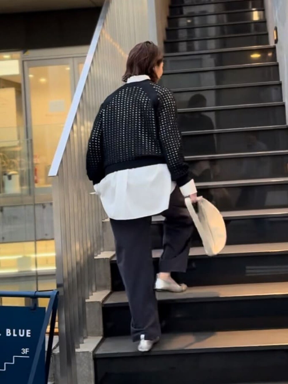 ブルー系のニット/セーター、ホワイト系のシャツ/ブラウス、ブルー系のチノパンツを着用したレディースの冬コーディネートの2枚目の写真