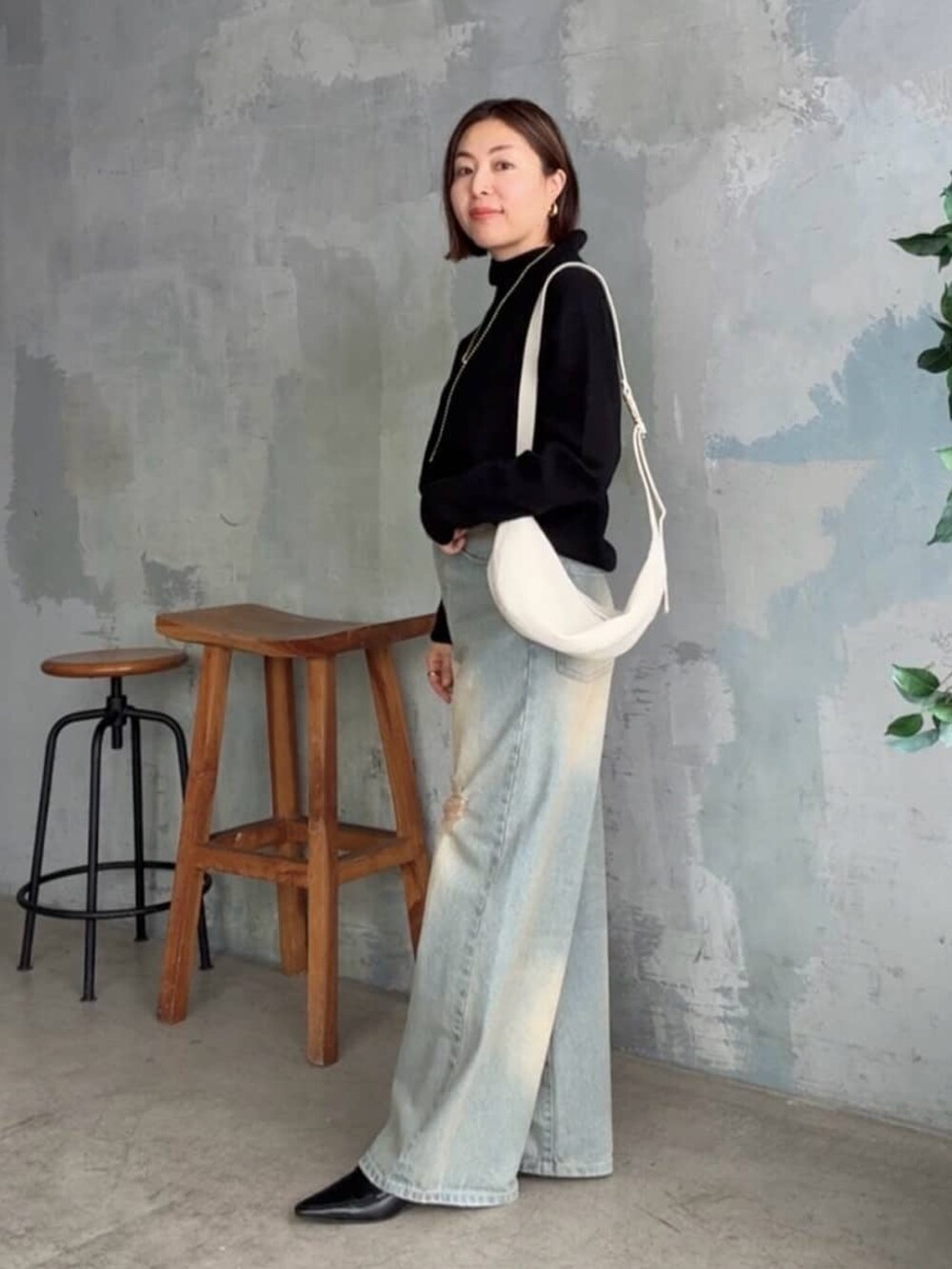 ブラック系のニット/セーター、ブルー系のデニムパンツ、ブラック系のローファーを着用したレディースの秋コーディネートの2枚目の写真