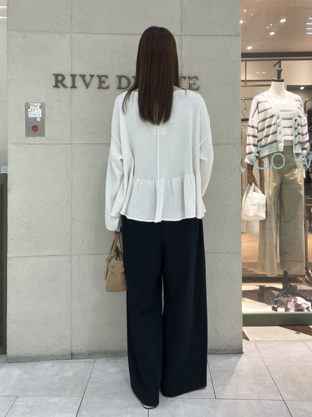 ベージュ系のトートバッグ、ブラウン系のその他シューズ、ホワイト系のニット/セーターを着用したレディースの春コーディネートの3枚目の写真