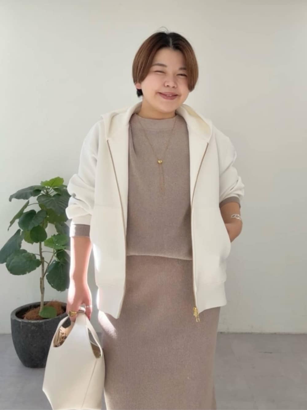 ホワイト系のハンドバッグ、ホワイト系のパーカー、ブラウン系のニット/セーターを着用したレディースの冬コーディネートの6枚目の写真