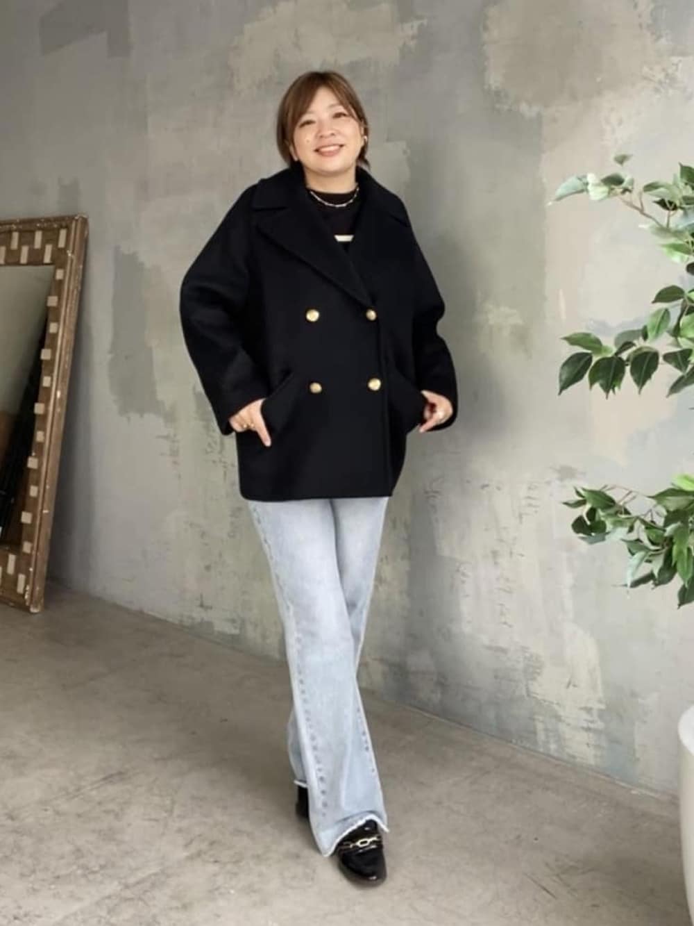 ブラック系のニット/セーター、ブルー系のデニムパンツ、ブラック系のピーコートを着用したレディースの秋コーディネートの5枚目の写真