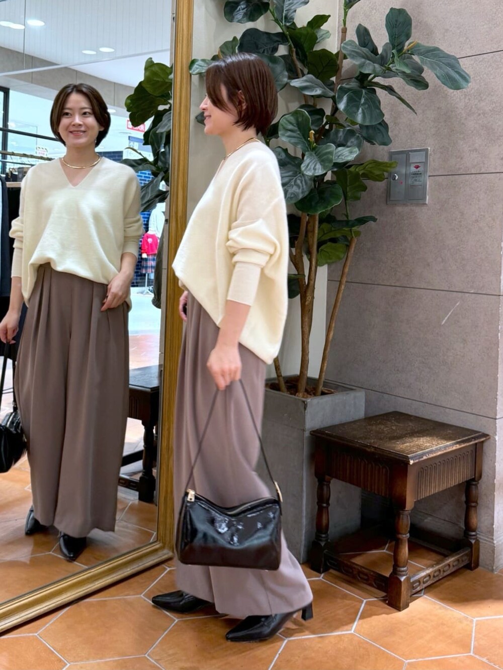 ホワイト系のニット/セーター、ブラウン系のスラックス、ブラック系のショルダーバッグを着用したレディースの冬コーディネートの2枚目の写真