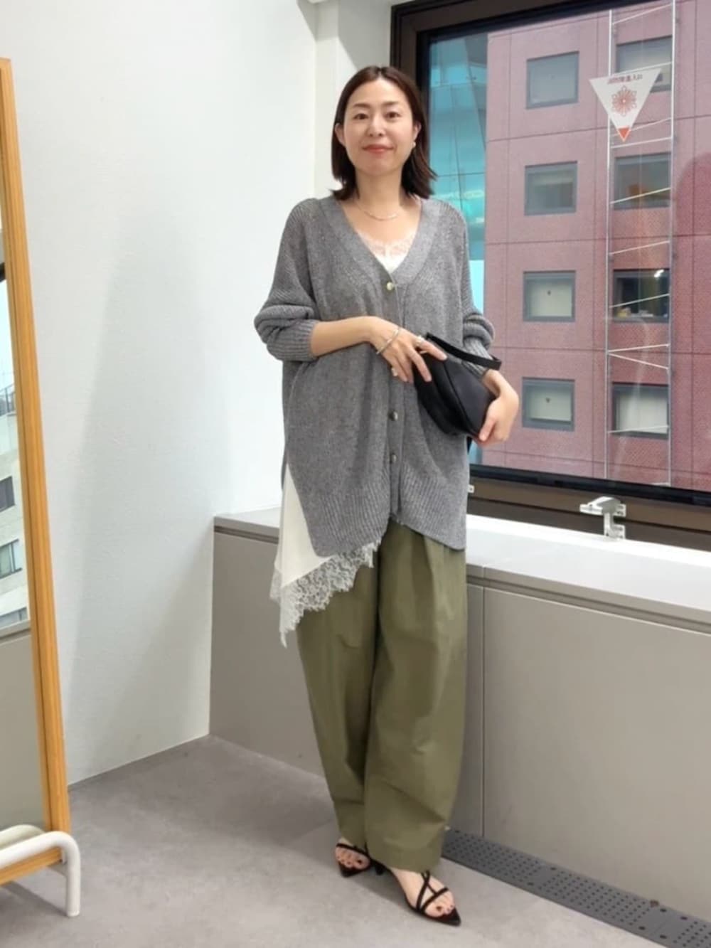 ブラック系のサンダル、ホワイト系のキャミソール、ブラック系のショルダーバッグを着用したレディースの春コーディネートの4枚目の写真