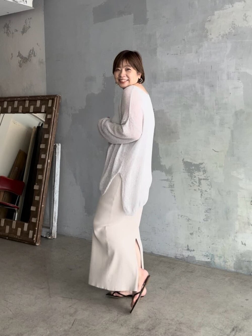 グレー系のニット/セーター、ホワイト系のスカート、グレー系のタンクトップを着用したレディースの春コーディネートの2枚目の写真