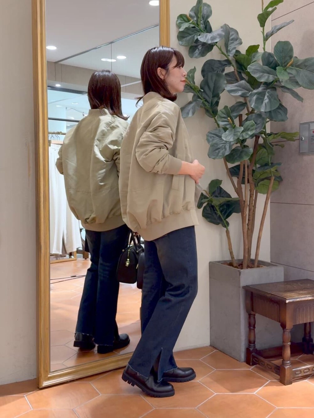 ベージュ系のMA-1、ブラック系のボストンバッグ、ブルー系のデニムパンツを着用したレディースの秋コーディネートの2枚目の写真