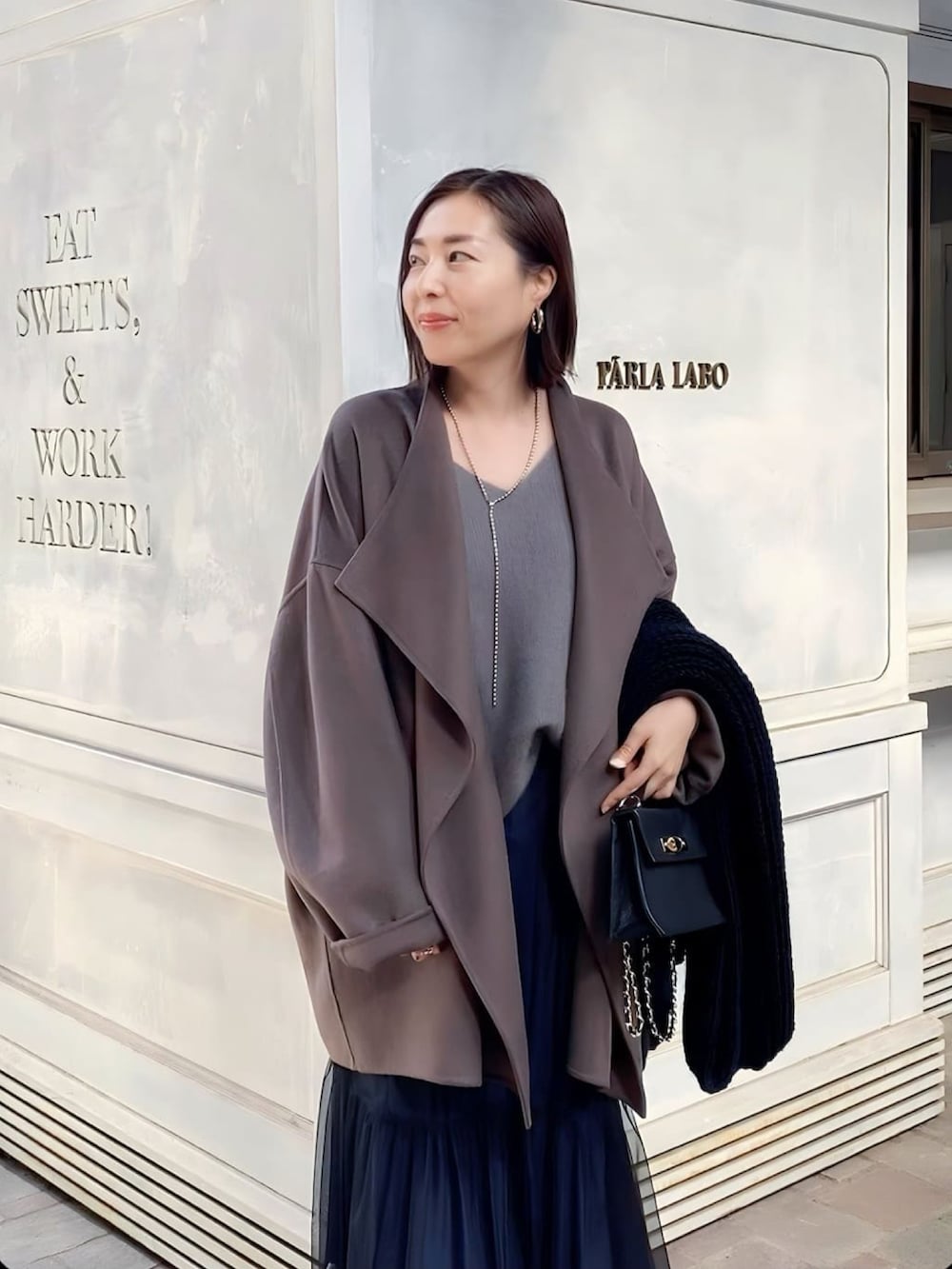 ブラウン系のその他アウター、ブラック系のスカート、ブラック系のハンドバッグを着用したレディースの秋コーディネートの4枚目の写真