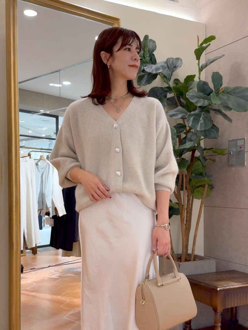 ベージュ系のボストンバッグ、ベージュ系のカーディガン/ボレロ、ベージュ系のスカートを着用したレディースの秋コーディネートの4枚目の写真