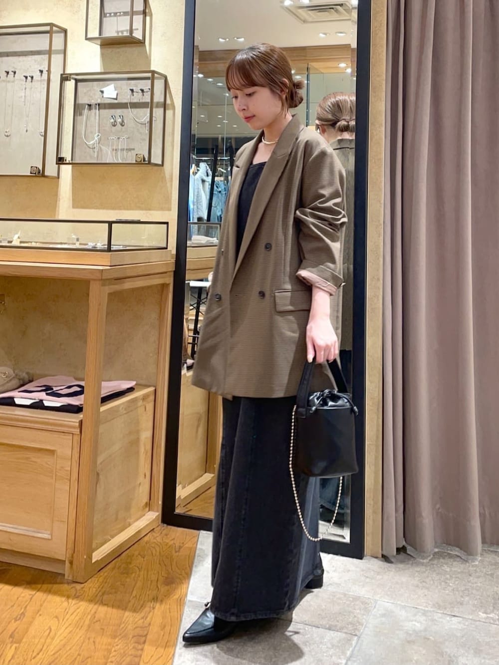 ブラウン系のテーラードジャケット、ブラック系のワンピース、ブラック系のハンドバッグを着用したレディースの秋コーディネートの3枚目の写真