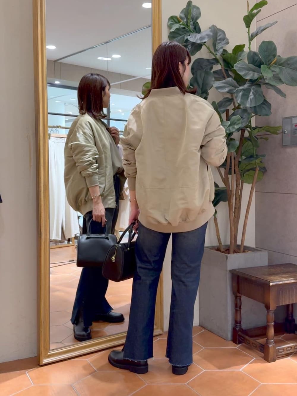 ベージュ系のMA-1、ブラック系のボストンバッグ、ブルー系のデニムパンツを着用したレディースの秋コーディネートの3枚目の写真