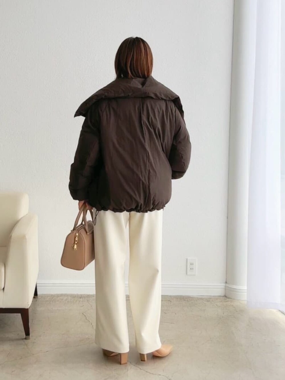 ブラウン系のダウンジャケット/コート、ベージュ系のバッグ、ホワイト系のその他パンツを着用したレディースの秋コーディネートの3枚目の写真