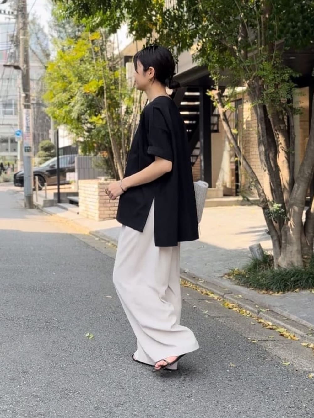 ブラック系のTシャツ/カットソー、グレー系のスラックス、ホワイト系のトートバッグを着用したレディースの春コーディネートの2枚目の写真