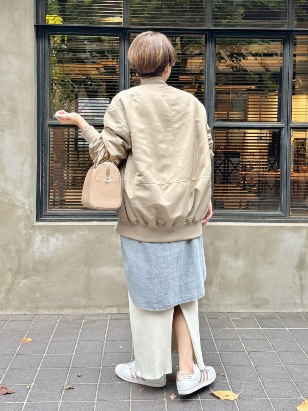 ベージュ系のバッグ、グレー系のニット/セーター、ベージュ系のスカートを着用したレディースの秋コーディネートの3枚目の写真