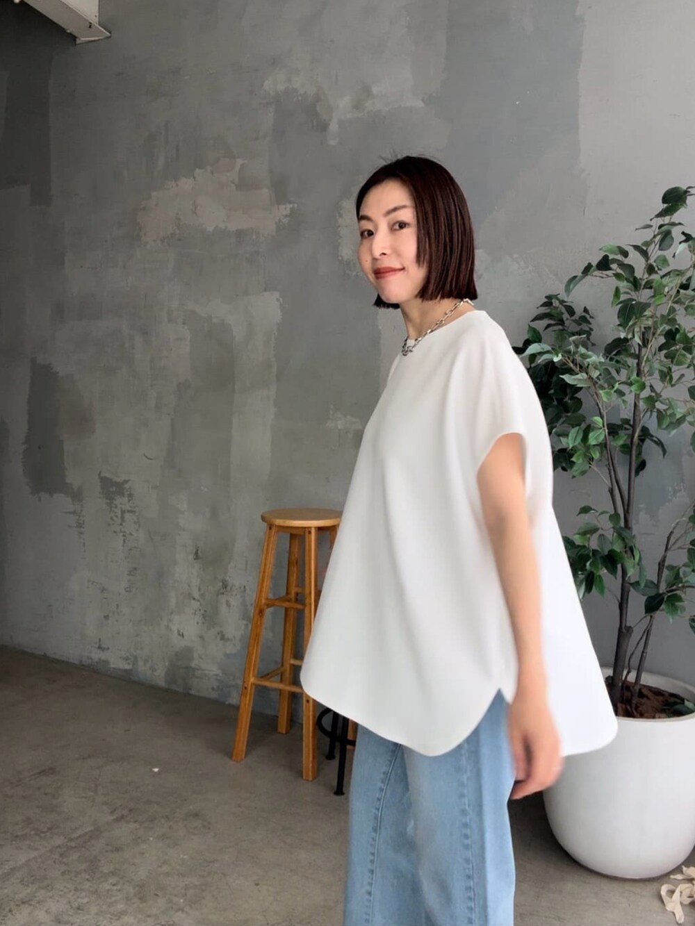 ブルー系のデニムパンツ、ブラック系のサンダル、ホワイト系のハンドバッグを着用したレディースの春コーディネートの4枚目の写真