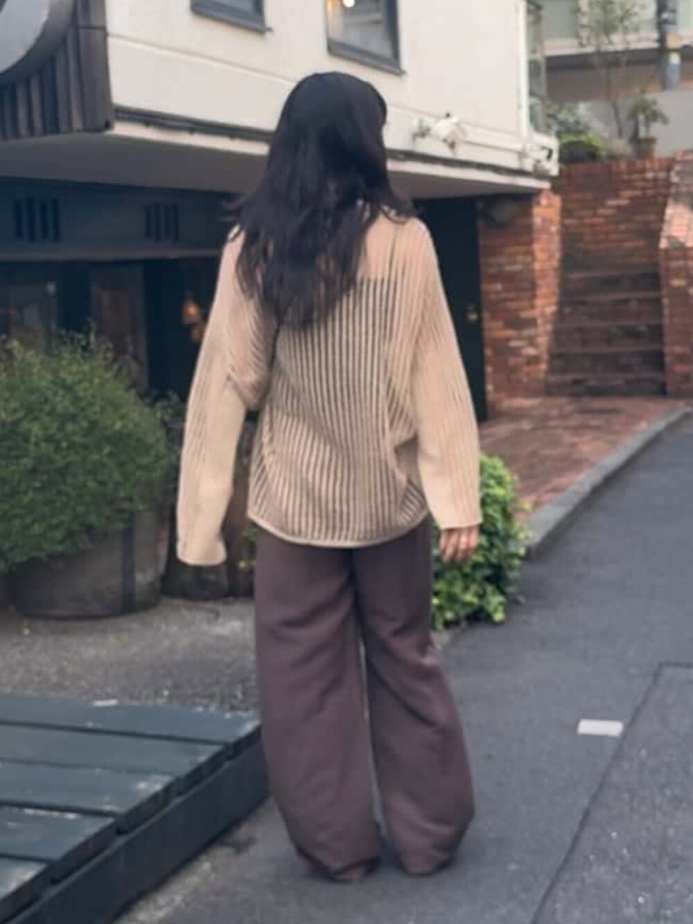 ホワイト系のニット/セーター、ブラウン系のスラックス、ブラック系のサンダルを着用したレディースの春コーディネートの3枚目の写真