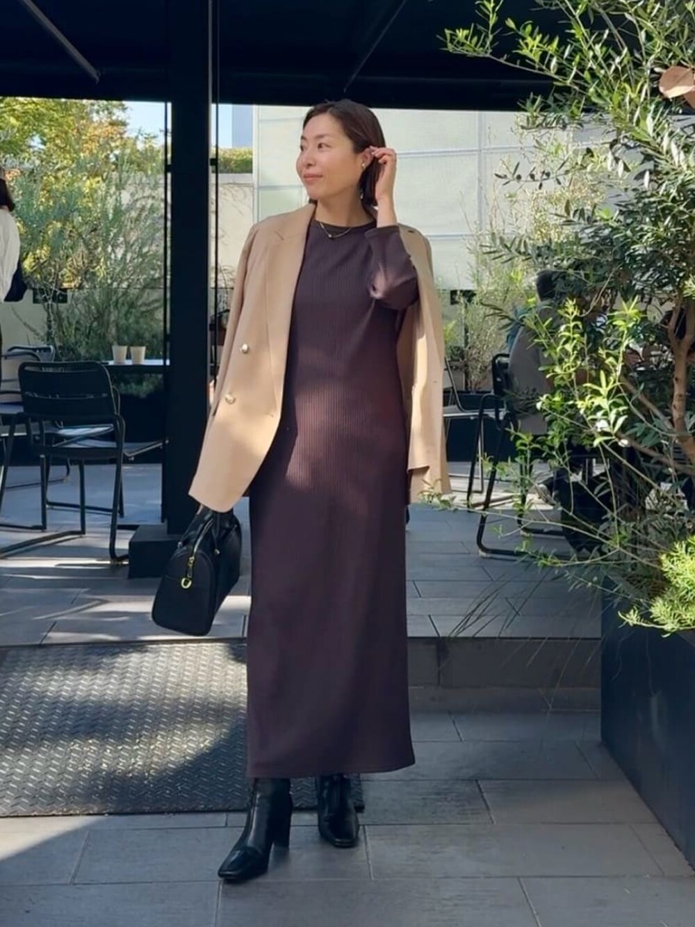 イエロー系のテーラードジャケット、ブラウン系のワンピース、ブラック系のバッグを着用したレディースの秋コーディネートの4枚目の写真