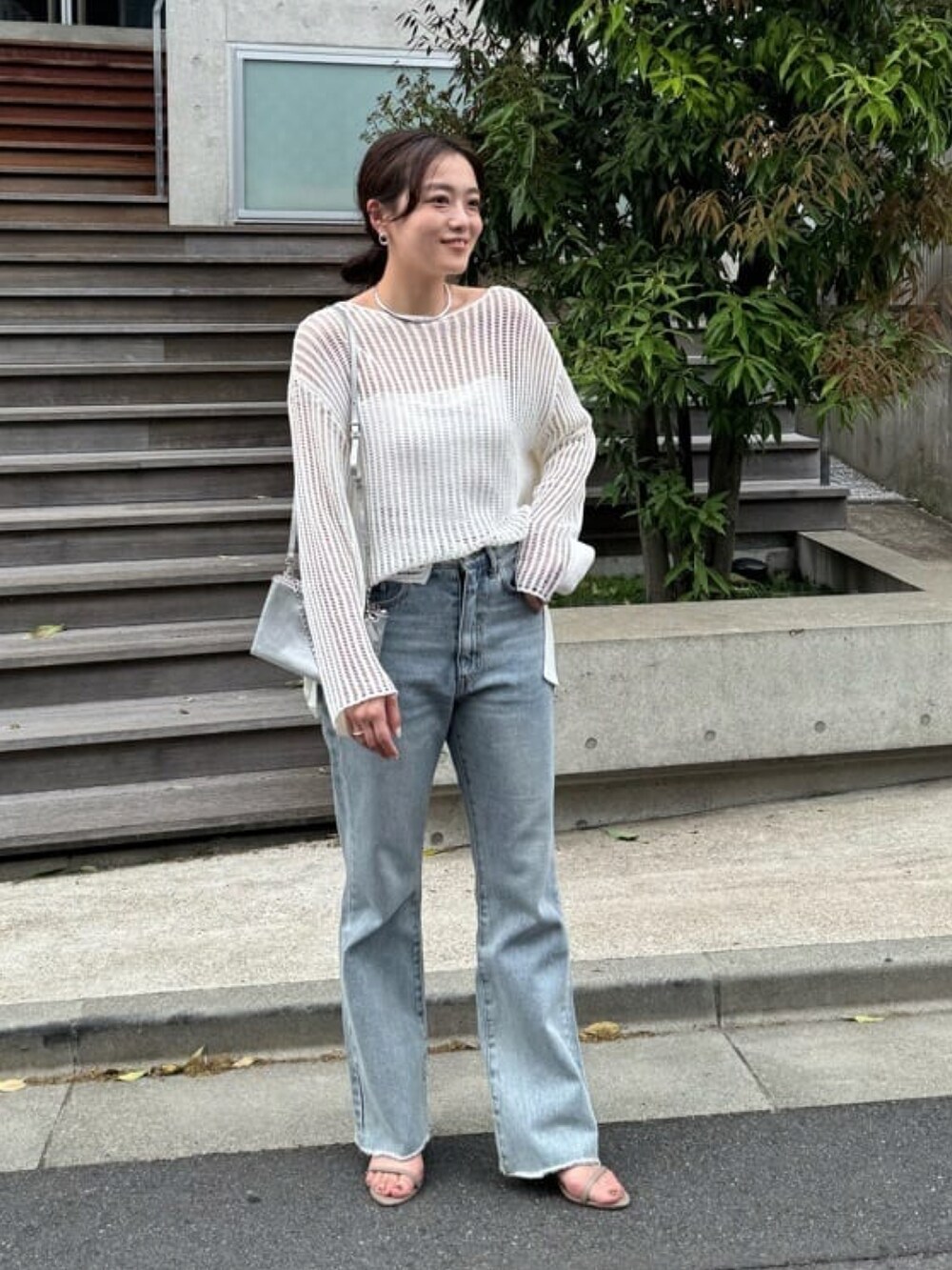 ホワイト系のニット/セーター、ブルー系のデニムパンツ、グレー系のサンダルを着用したレディースの春コーディネートの3枚目の写真