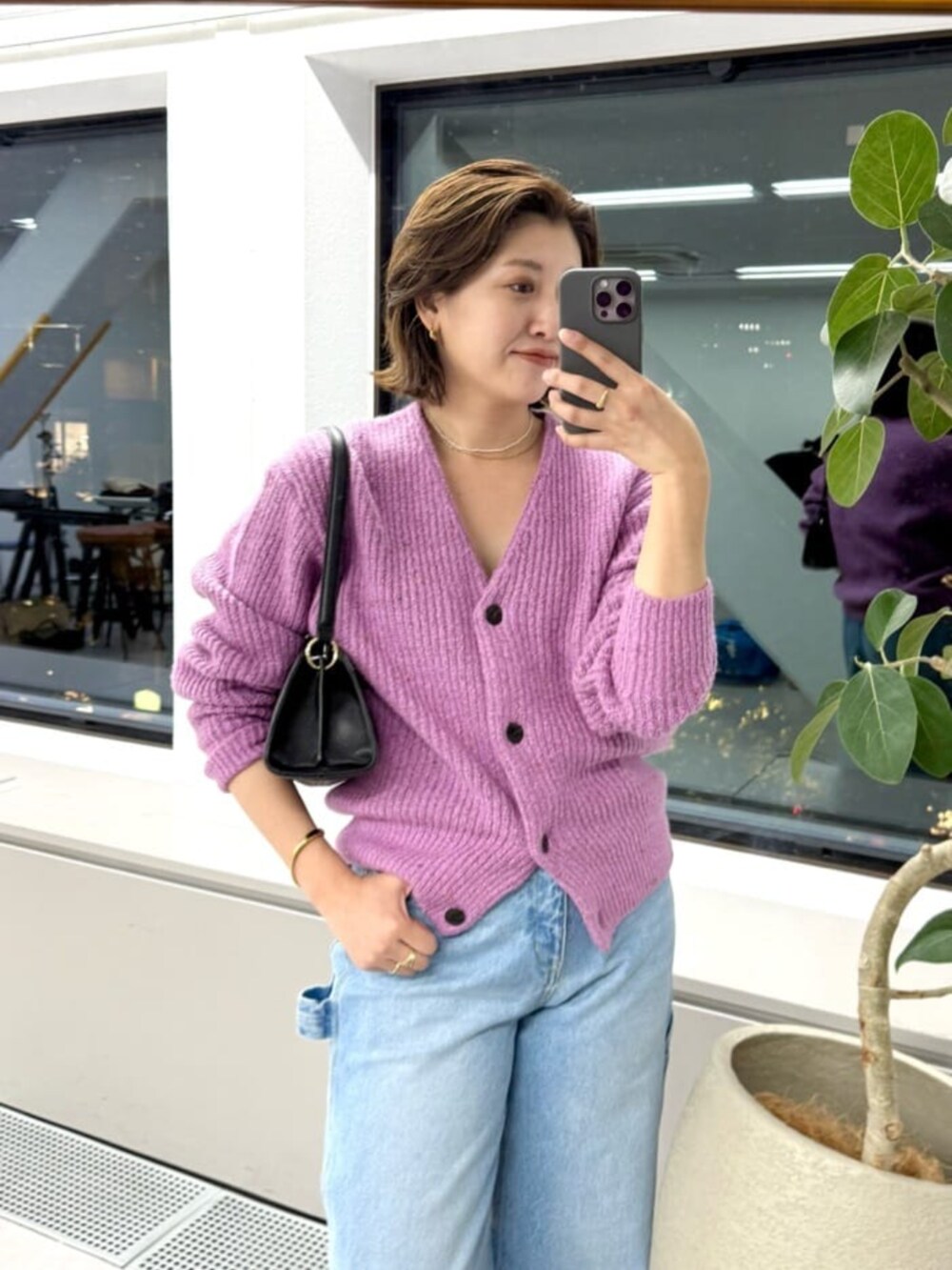 ブルー系のデニムパンツ、ブラック系のハンドバッグ、ピンク系のカーディガン/ボレロを着用したレディースの秋コーディネートの2枚目の写真