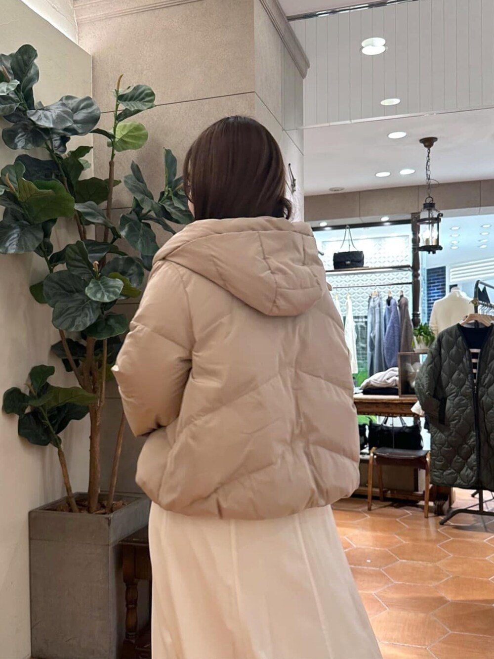 ブラック系のダウンジャケット/コート、ホワイト系のスカート、ブラック系のハンドバッグを着用したレディースの冬コーディネートの5枚目の写真