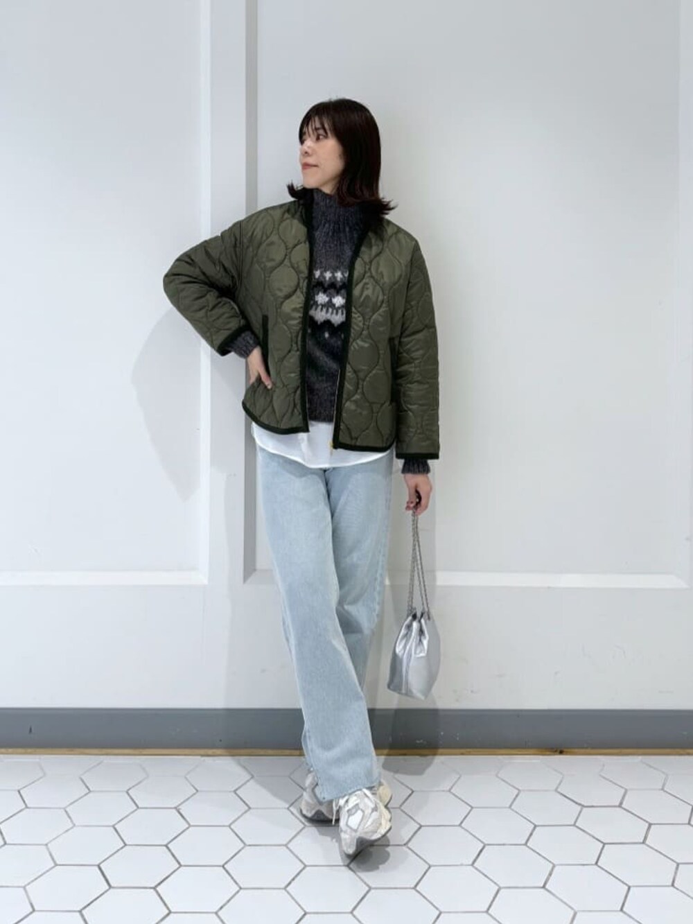グリーン系のダウンジャケット/コート、グレー系のニット/セーター、ブルー系のデニムパンツを着用したレディースの秋コーディネートの2枚目の写真