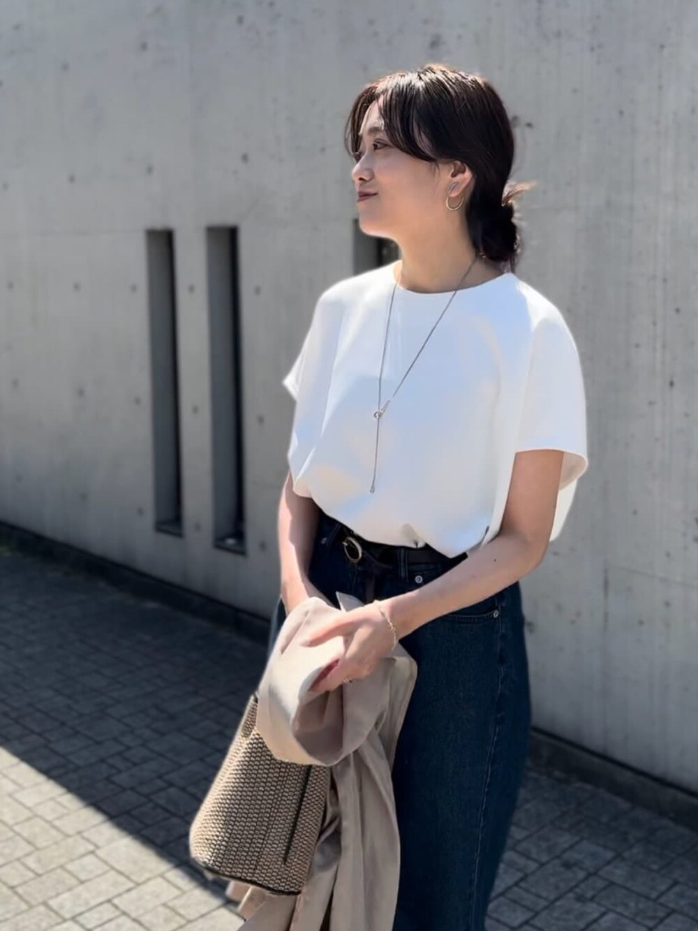 ブルー系のデニムパンツ、ブラック系のハンドバッグ、ブラック系のサンダルを着用したレディースの春コーディネートの4枚目の写真