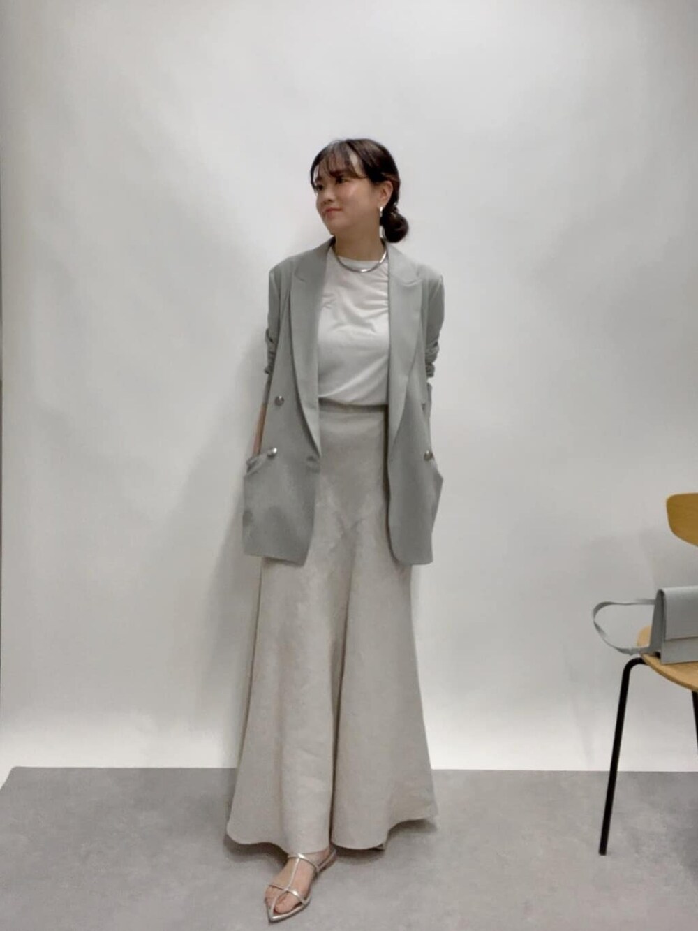 ベージュ系のテーラードジャケット、グリーン系のスカート、ブルー系のショルダーバッグを着用したレディースの春コーディネートの3枚目の写真