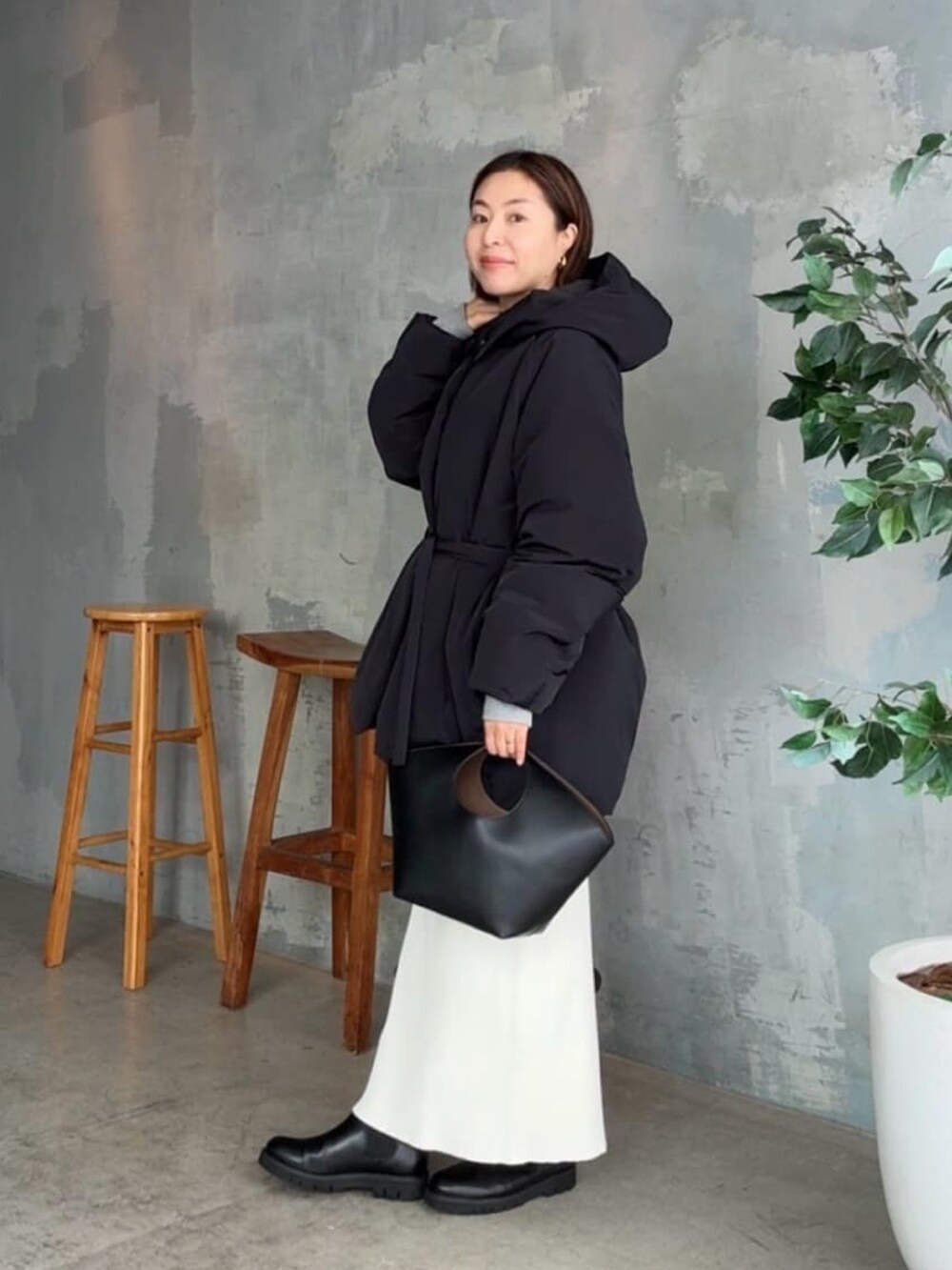 ブラック系のダウンジャケット/コート、ホワイト系のスカート、ブラック系のハンドバッグを着用したレディースの冬コーディネートの2枚目の写真