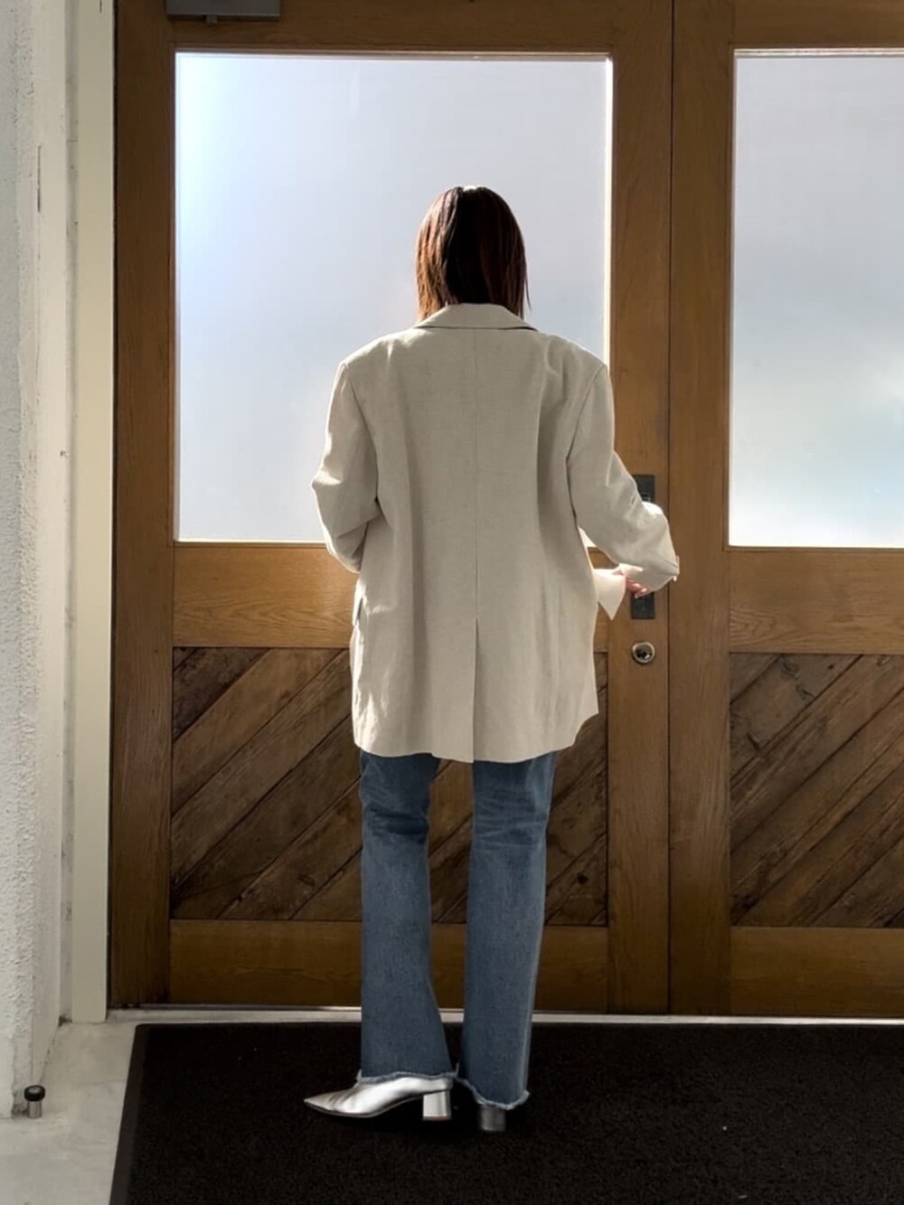 ホワイト系のニット/セーター、ベージュ系のテーラードジャケット、ブルー系のデニムパンツを着用したレディースの冬コーディネートの2枚目の写真