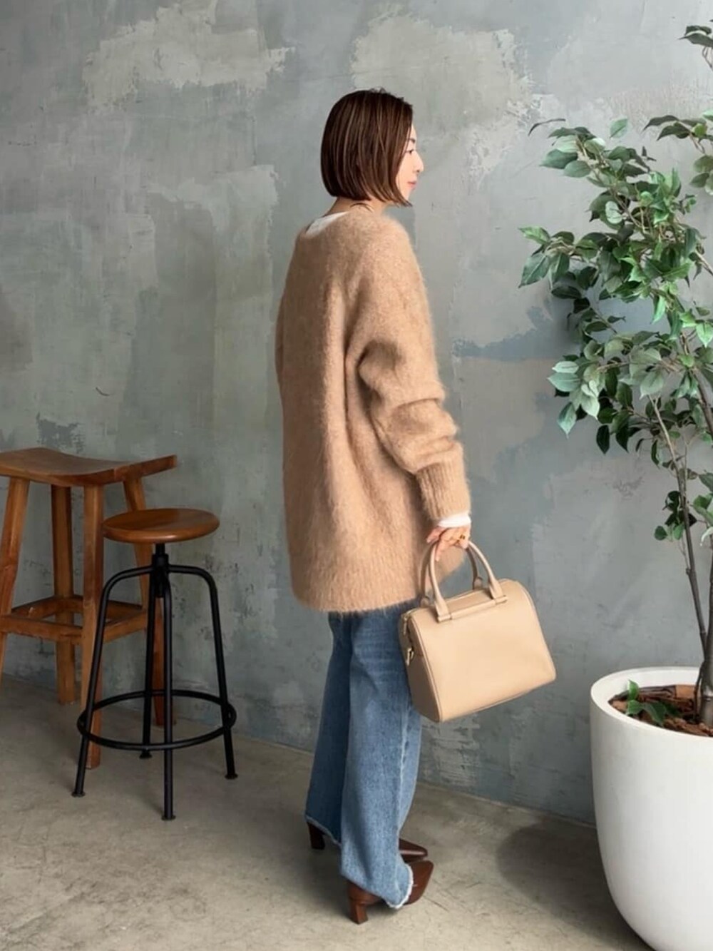 イエロー系のニット/セーター、ブルー系のデニムパンツ、ベージュ系のボストンバッグを着用したレディースの秋コーディネートの2枚目の写真